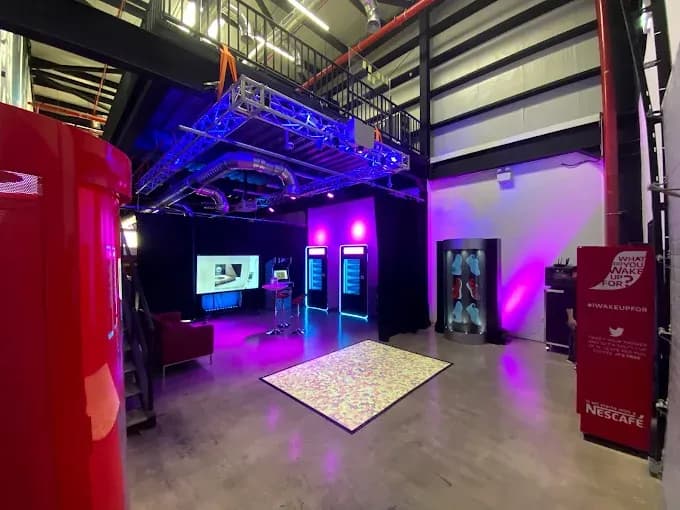 Modern interactive event space with purple and blue lighting and digital displays.